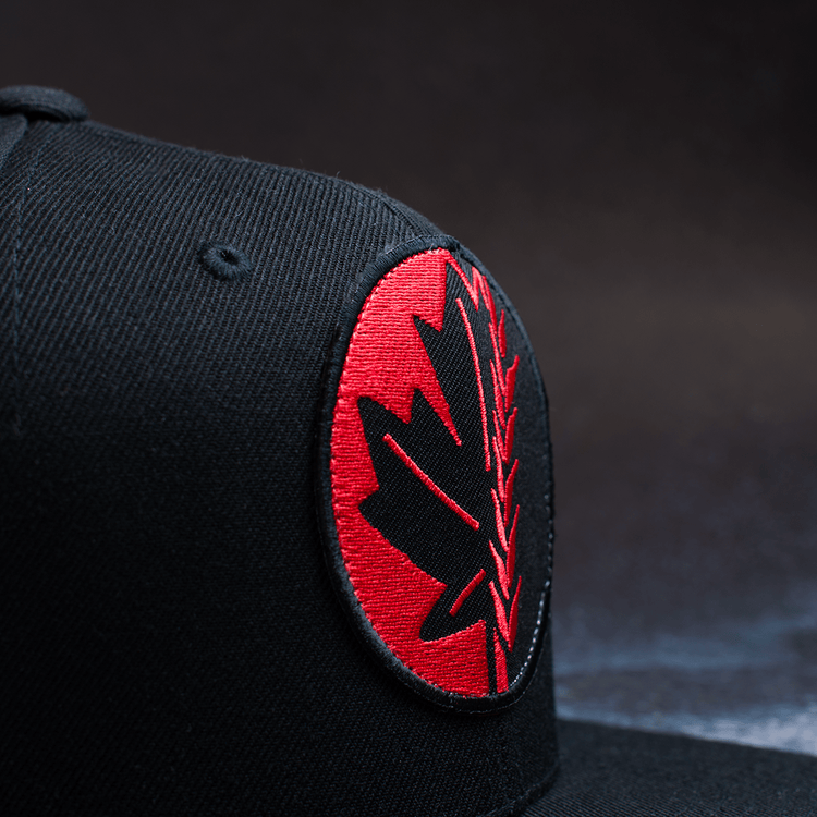 Black snapback hat with embroidered Fa Ram logo patch on the front. Close up of patch from left side.
