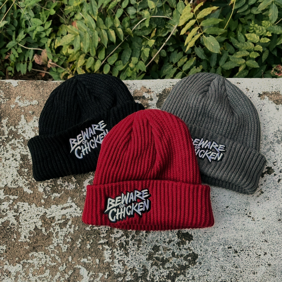 Photo of 3 x Beware Of Chicken embroidered beanies in maroon, black and grey on wall. 